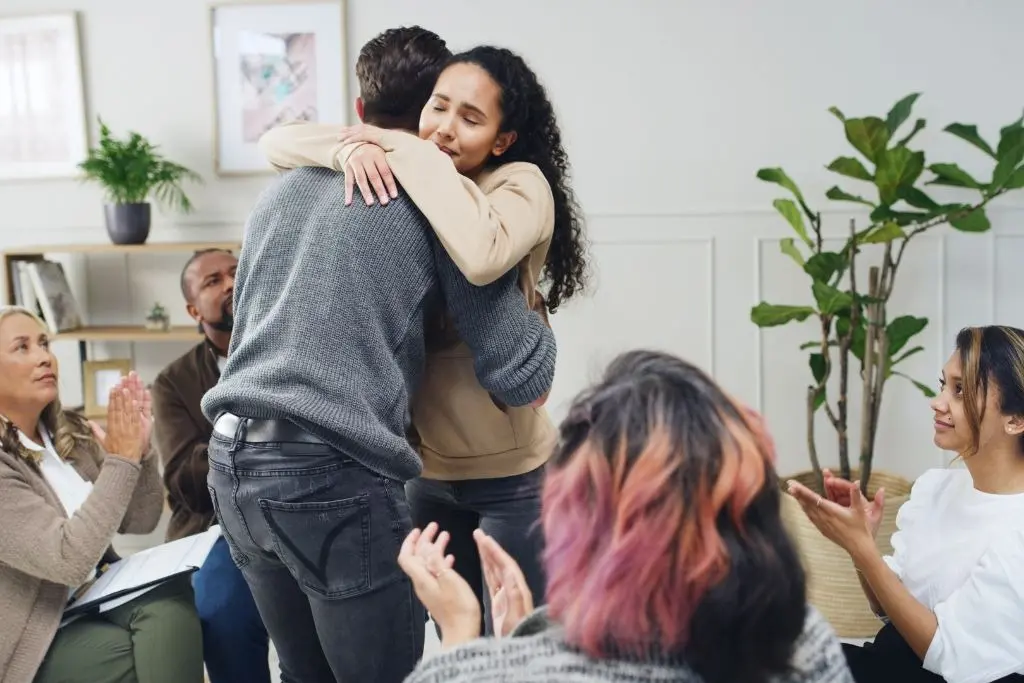 Group of people celebrating sobriety milestone with a hug.